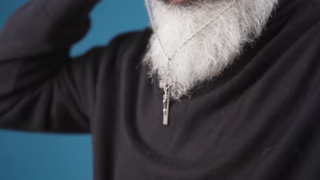 Religious-christian-man-with-white-beard-hangs-cross-necklace-around-his-neck.